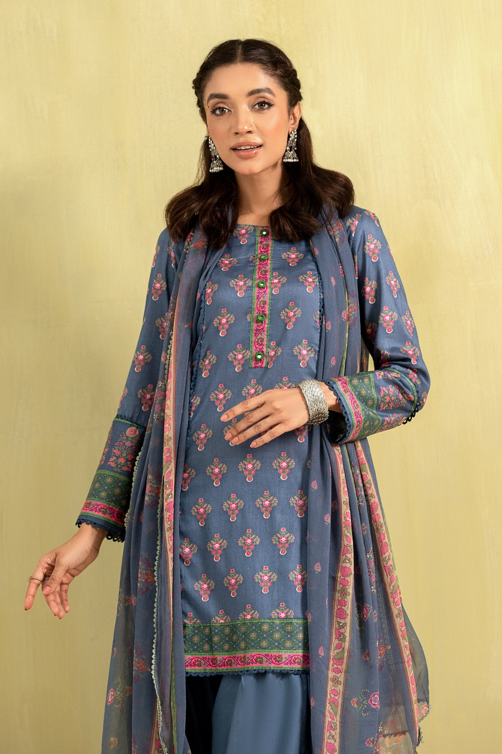 A girl is wearing a blue printed lawn outfit from Ittehad with a chiffon dupatta.