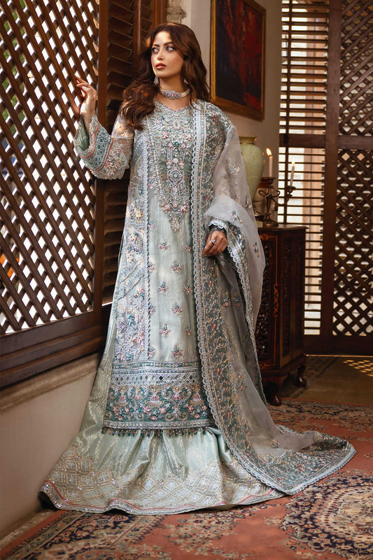 A woman wearing a traditional, embroidered organza lehnga with stone work and raw silk borders.
