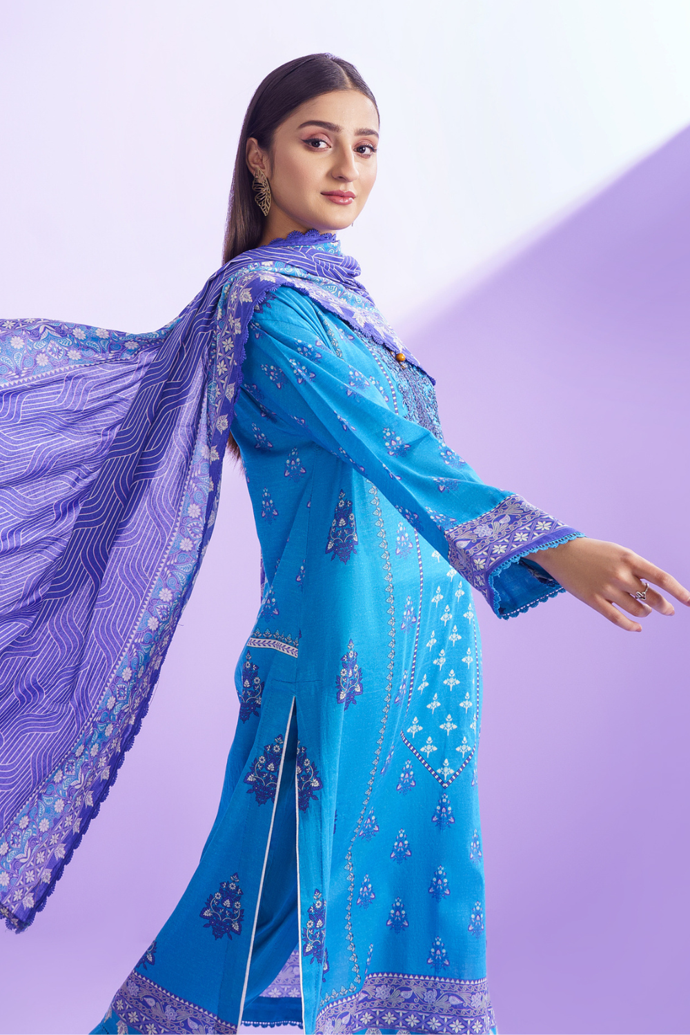 a woman wearing an ittehad embroidered salwar suit with purple dupatta.	