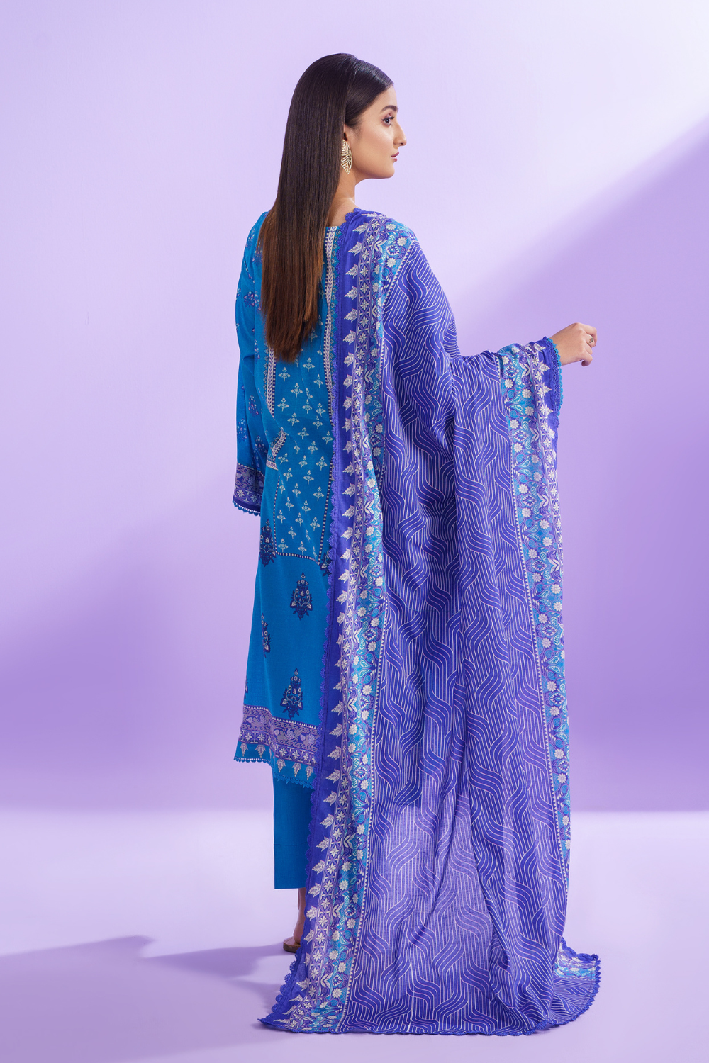 the back view of a woman wearing a blue and blue embroidered suit.	