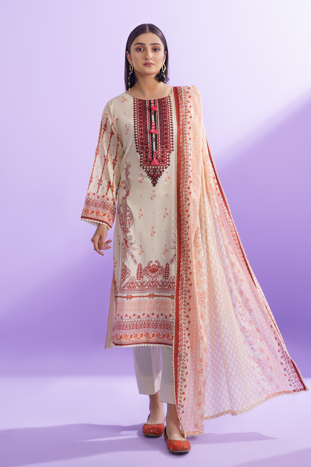 a woman wearing a beige and orange embroidered pakistani suit.