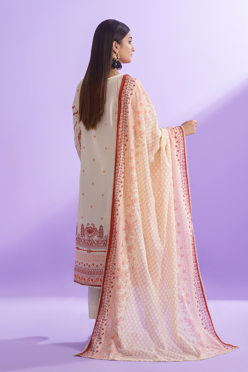 the back view of a woman wearing a white and skin embroidered suit.