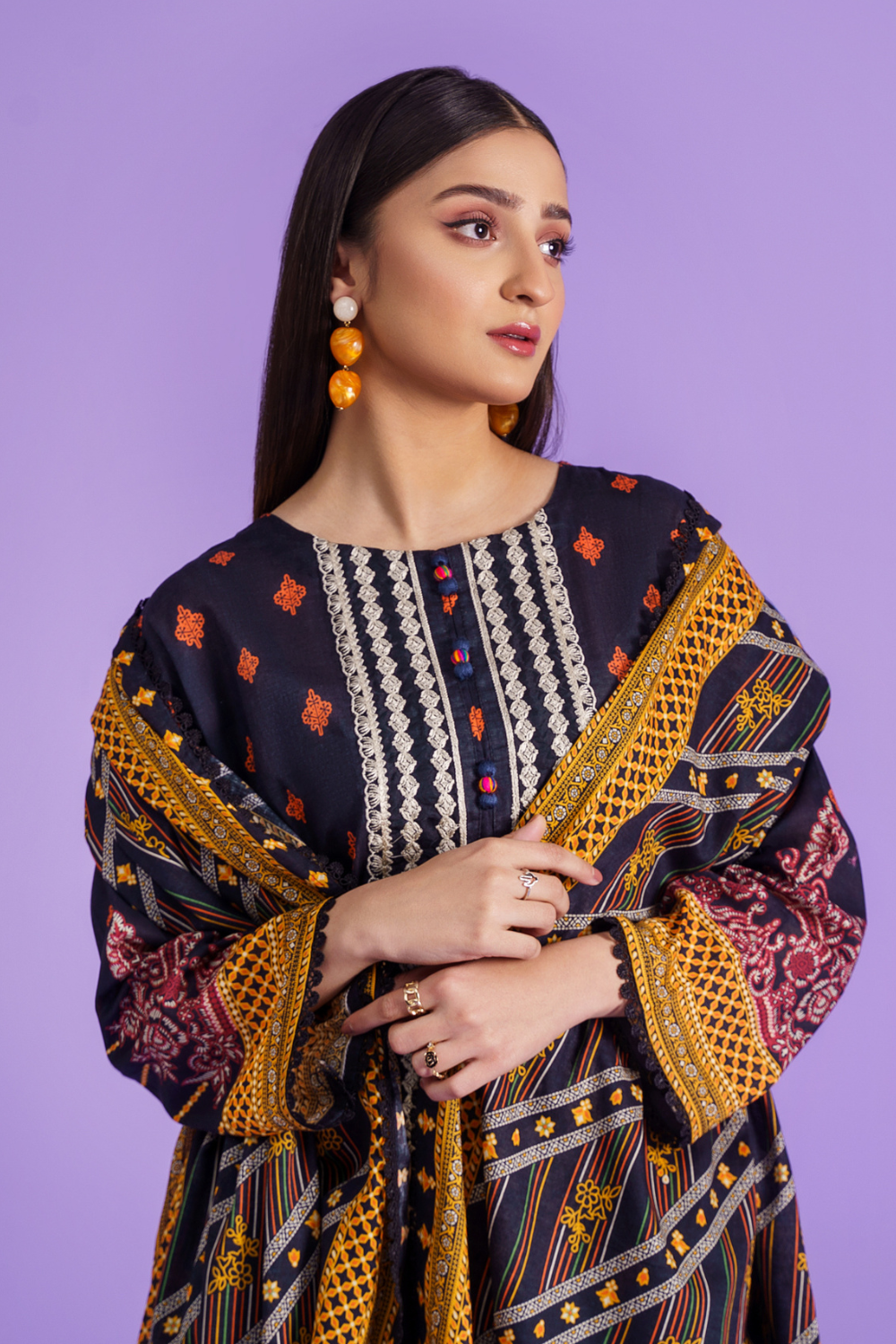 a woman wearing a dark greyand yellow embroidered suit.	