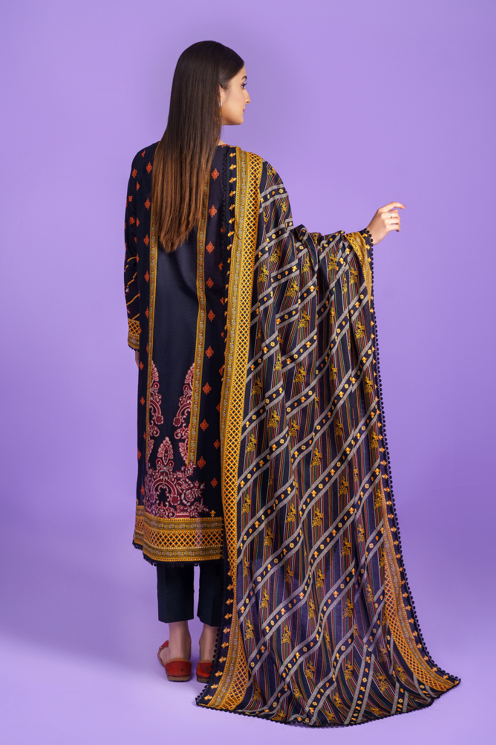 the back view of a woman wearing a dark grey and yellow embroidered suit.