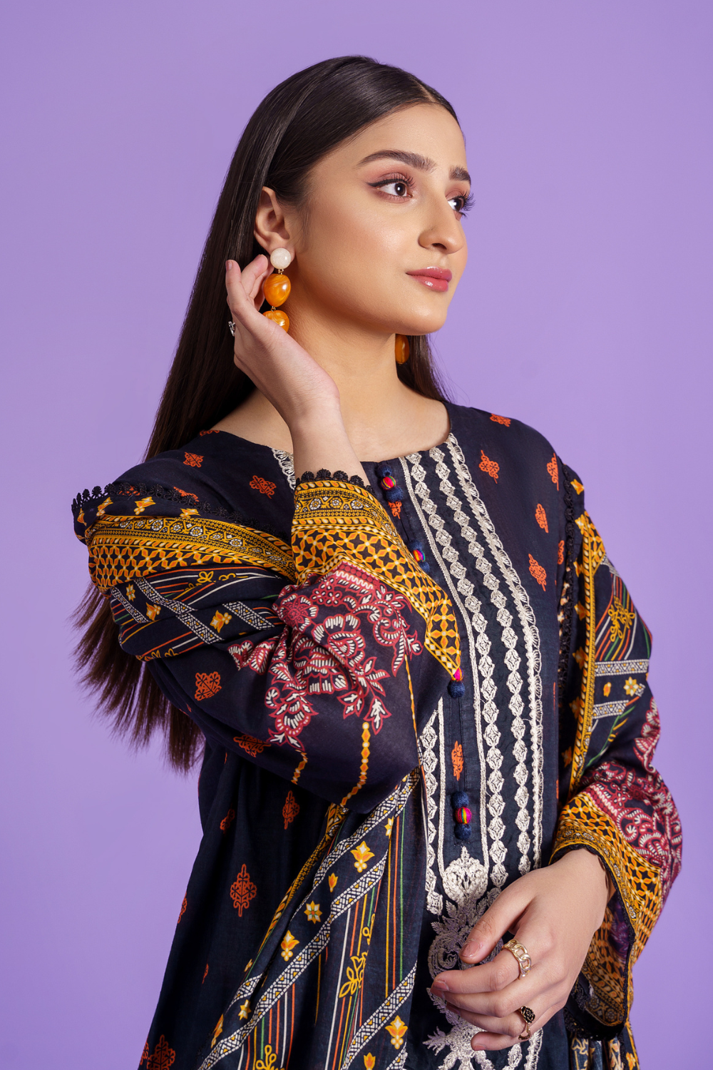 a woman wearing an embroidered dress and earrings.	