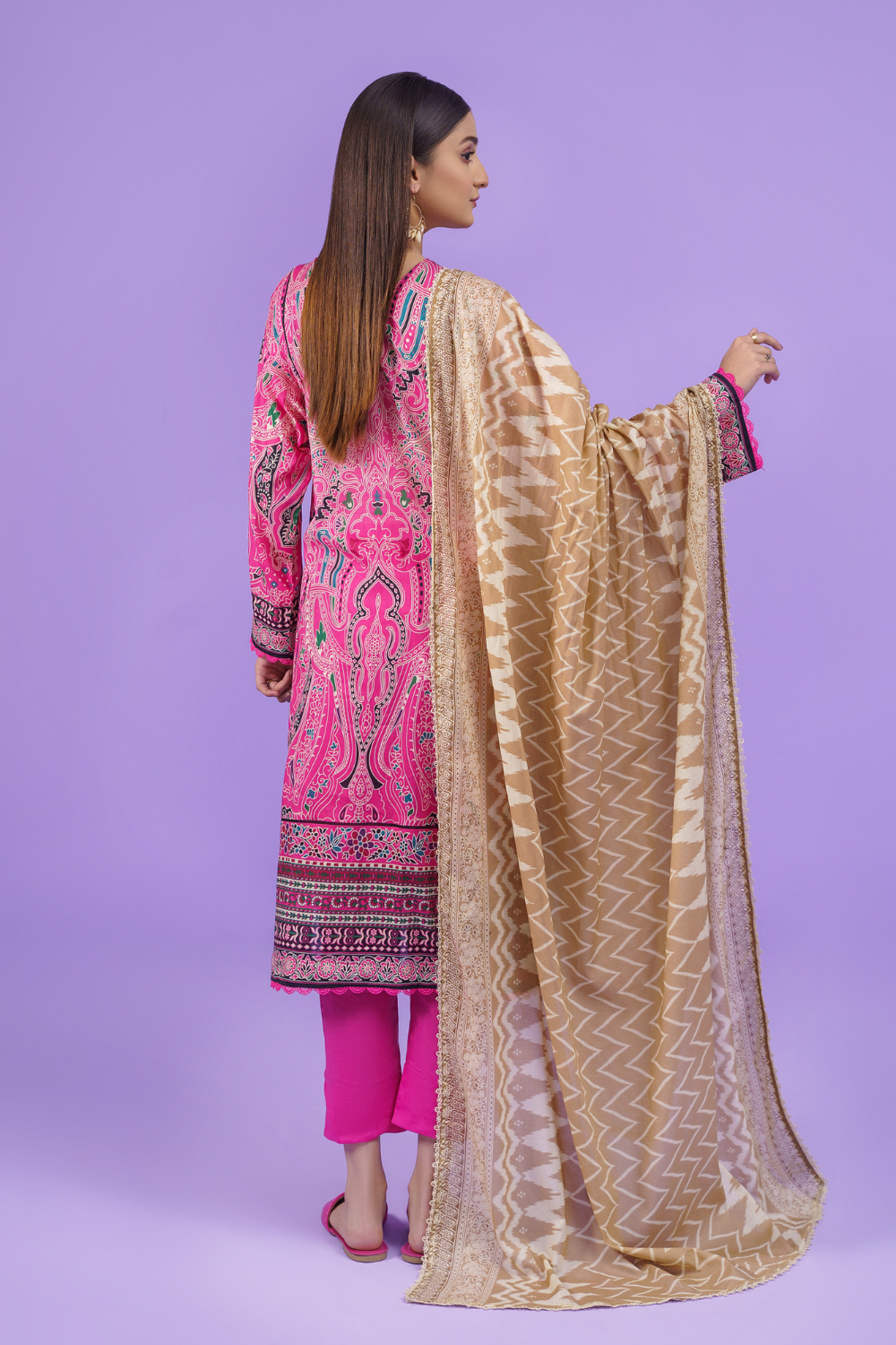 the back view of a woman wearing a pink and gold Ittehad embroidered suit.